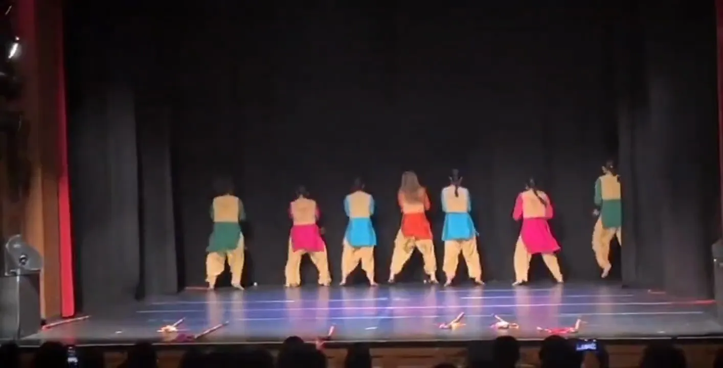 A bhangra team performing a choreographed routine on stage