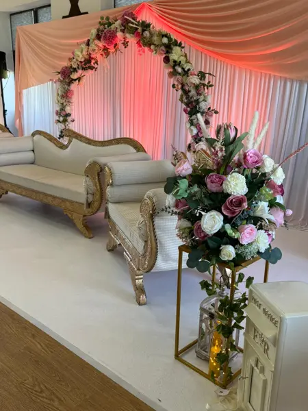 Pink floral arch with gold sofa
