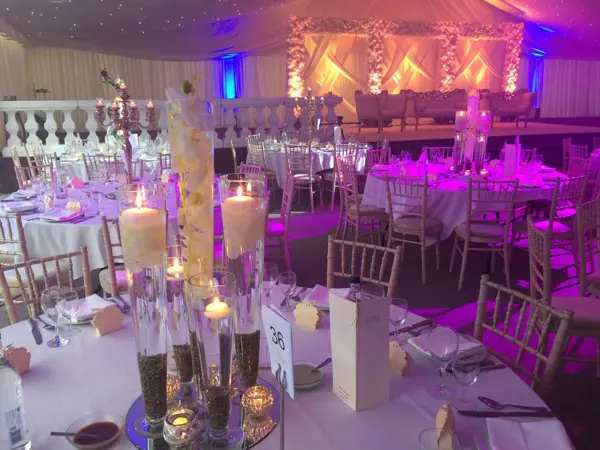 Purple-lit room with candle centrepieces and a stage backdrop