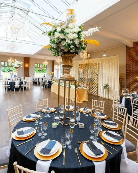 Navy tables with gold chargers and tall florals
