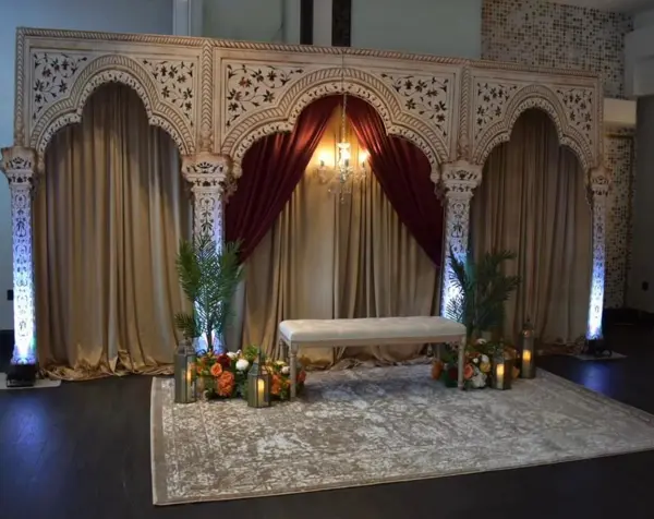 Carved arch backdrop with velvet drapes and a rug