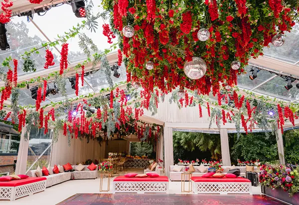 Glass marquee with red hanging floral ceiling and lounge seating