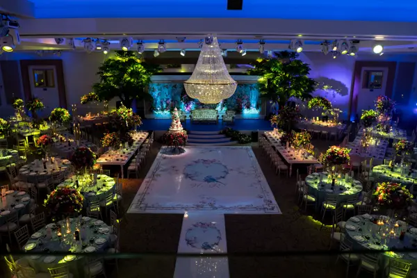 Ballroom styled as an enchanted garden with trees, chandelier and a white aisle
