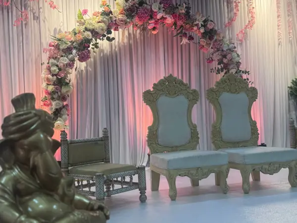 Floral arch with carved chairs and a Ganesh statue