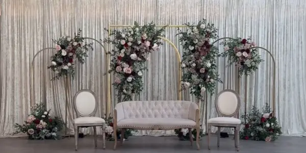 Floral stands and a white sofa against silver drapes