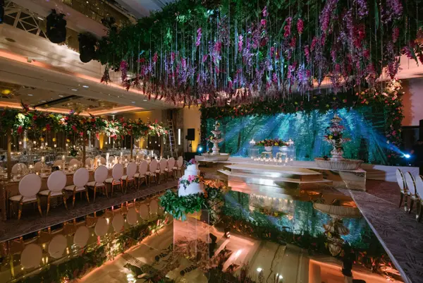 Ballroom with a hanging floral ceiling, long tables and a lit stage
