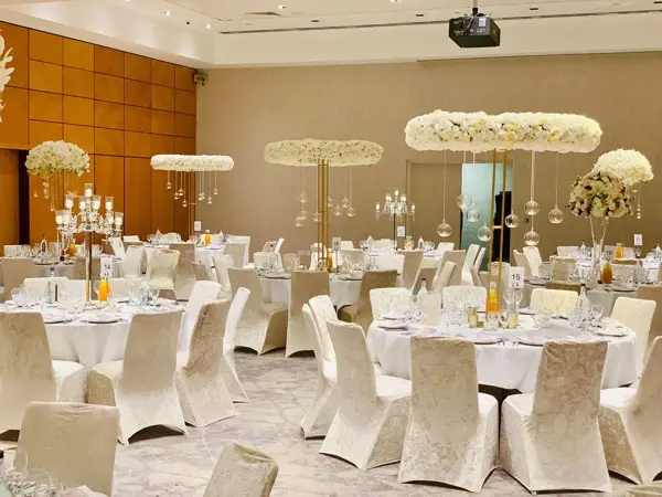 White chair covers and floating floral centrepieces in a ballroom