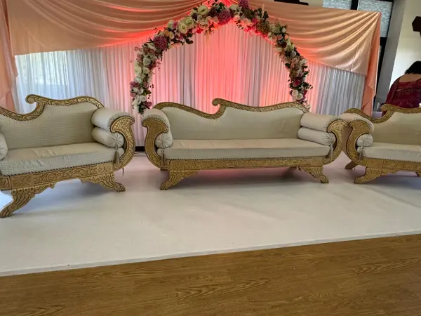 Pink-lit floral arch with gold sofas