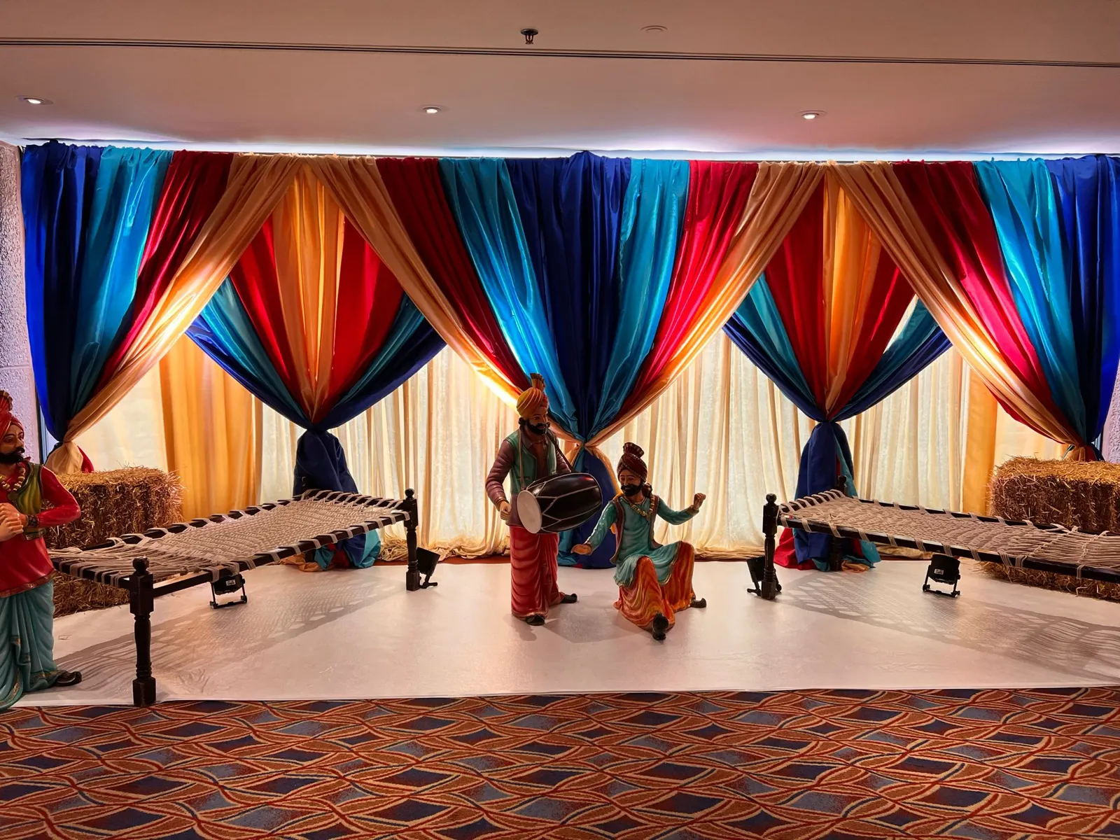 Colourful jago setup with drapes and a charpai