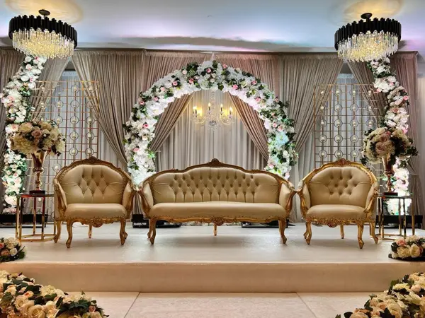 Gold sofas under a white floral arch on a stage
