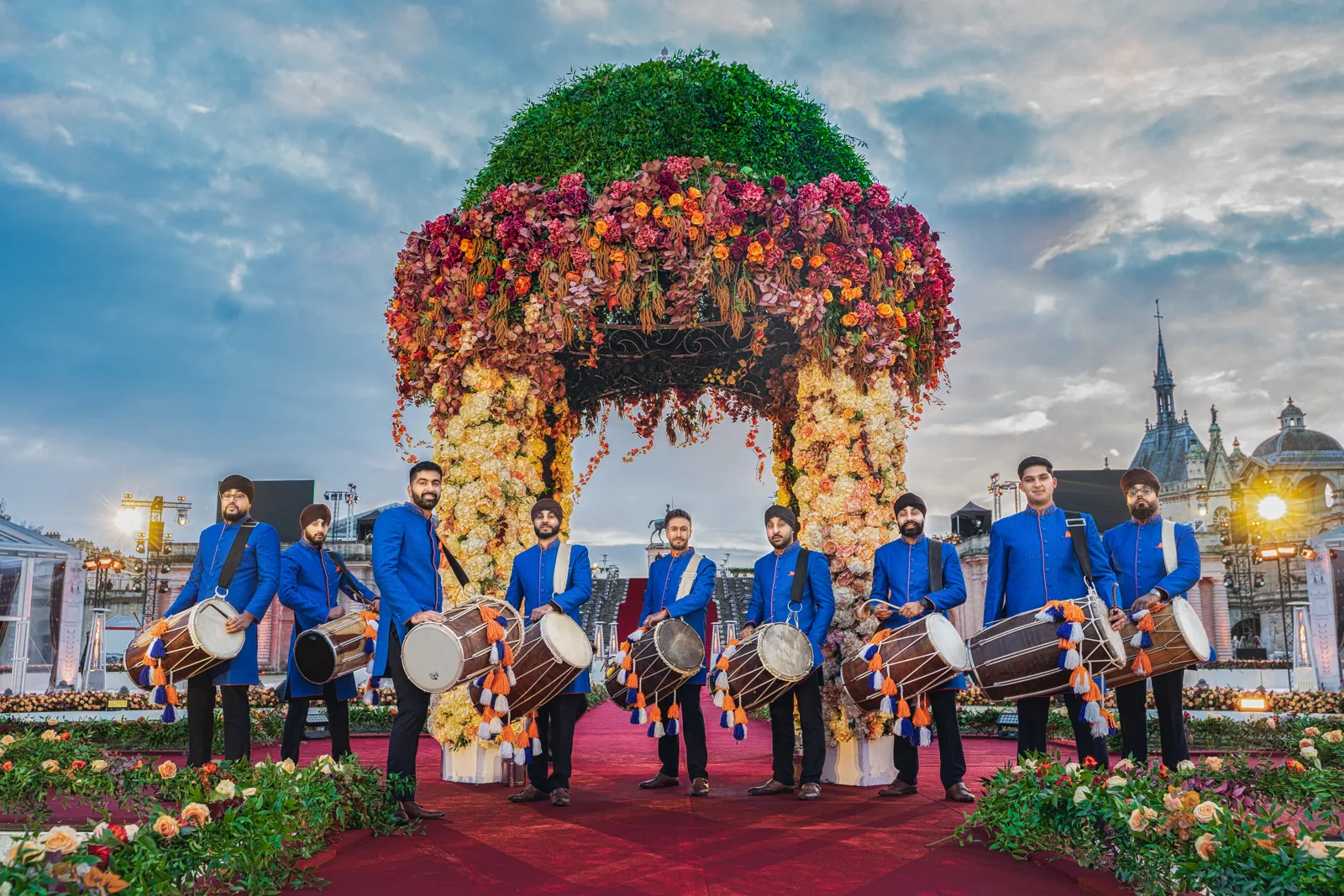Dhol players beside a floral mandap at a wedding in Paris