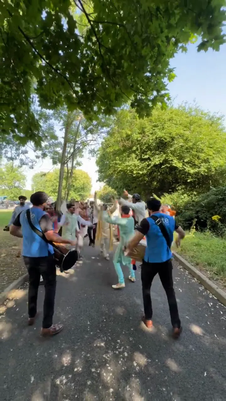 Two dhol players leading a baraat outdoors