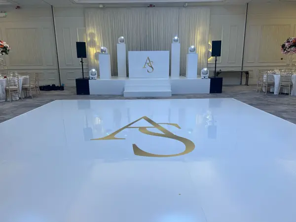 White DJ booth and a white gloss dance floor with gold initials
