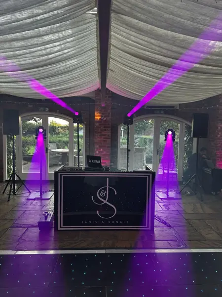 DJ booth with purple uplighting under a draped marquee