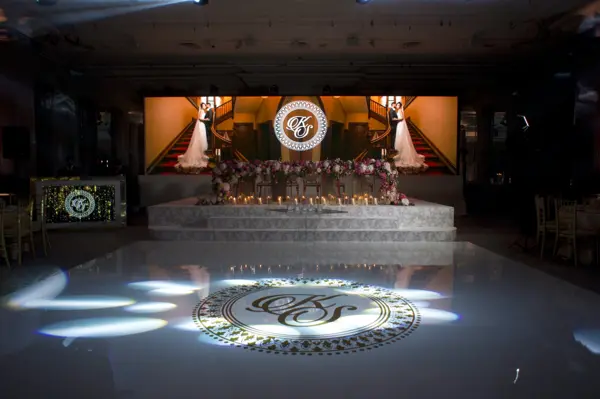 Monogram projected on a white dance floor in front of a stage at Grosvenor House