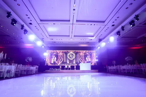 Ballroom lit purple with an LED stage and white dance floor