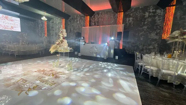 Lit dance floor and stage screen at a wedding reception