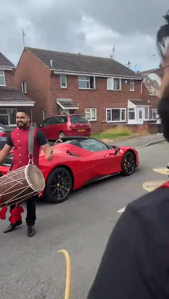 Band baja and dhol players in red sherwanis leading a baraat