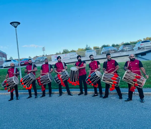 Band baja and dhol team in red sherwanis lined up outside a venue
