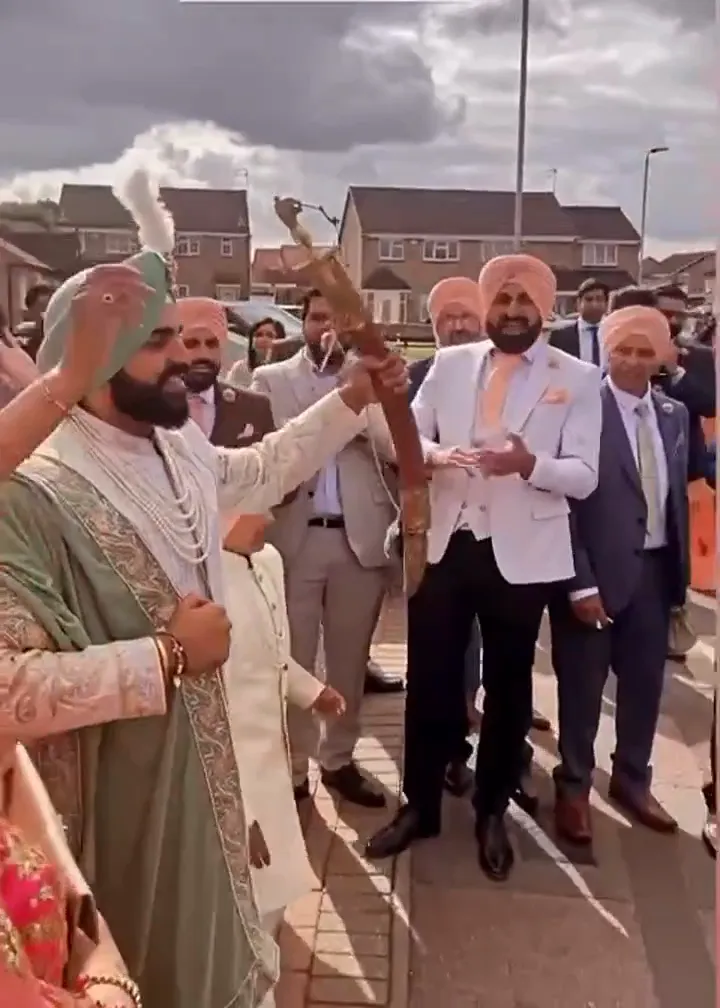 Band baja and dhol players in red sherwanis leading a baraat