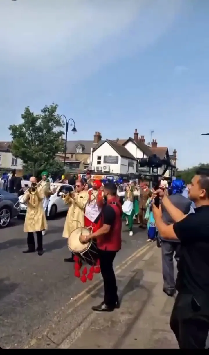 Band baja and dhol players in red sherwanis leading a baraat