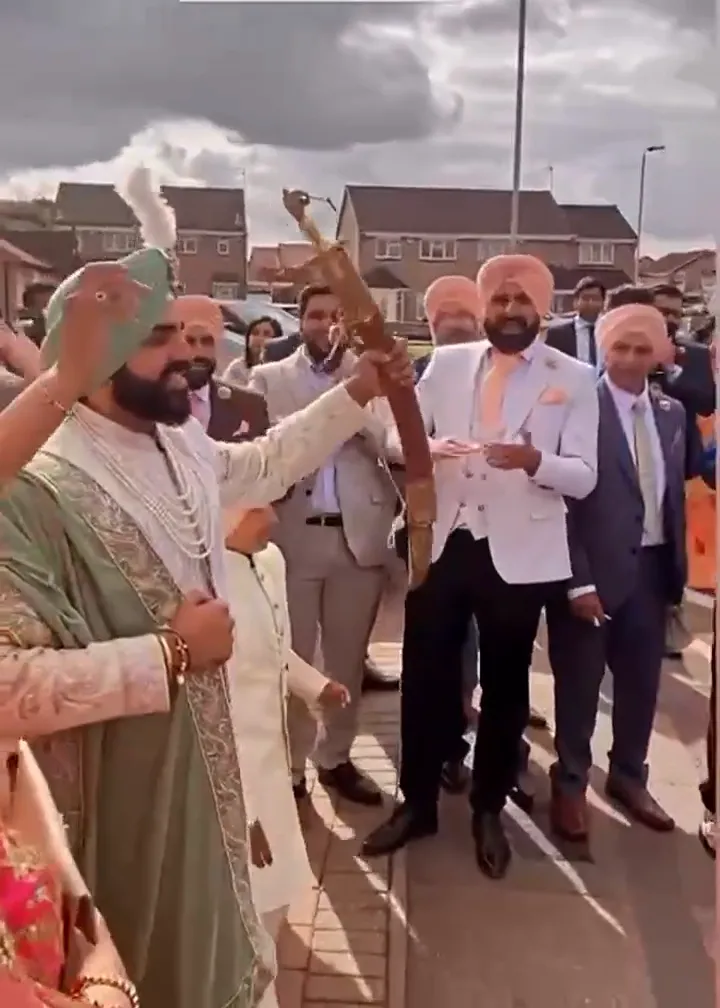 Band baja and dhol players in red sherwanis leading a baraat