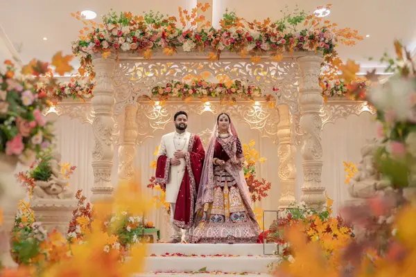 Bride and groom at a mandap with orange and gold flowers