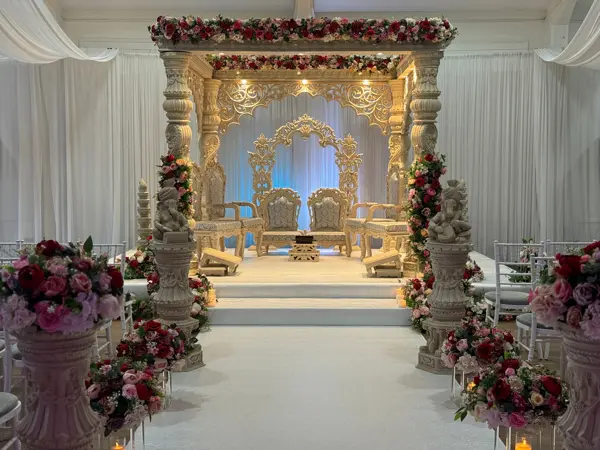 Carved mandap with floral urns either side of the aisle