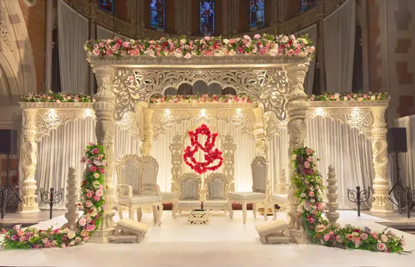 Carved mandap with a Ganesh backdrop and floral garlands