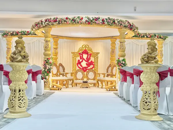 Gold mandap with a Ganesh backdrop and pillar urns