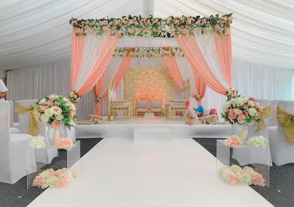 Mandap with peach drapes in a marquee
