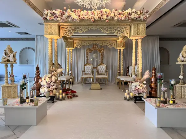 Gold temple-style mandap with statues lining the aisle