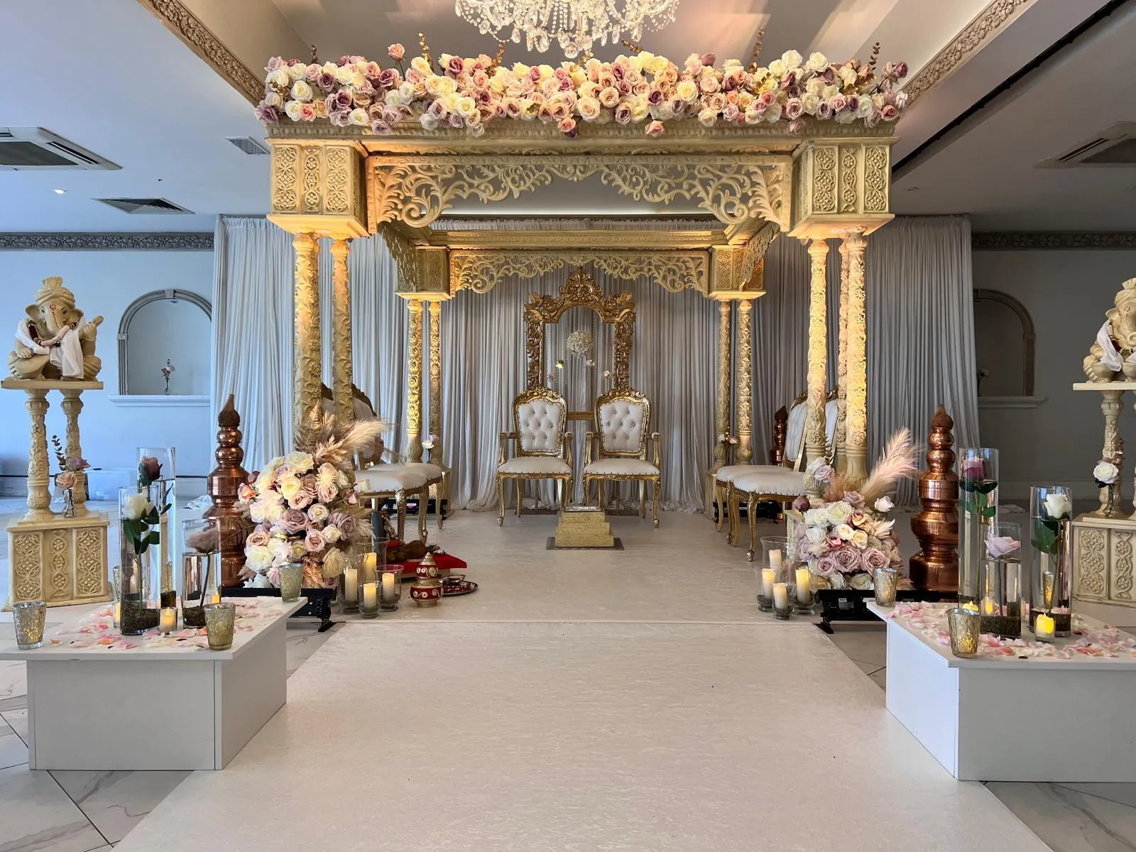Gold temple-style mandap with statues lining the aisle