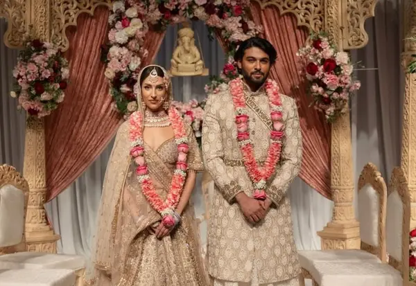 Bride and groom wearing garlands in front of the mandap