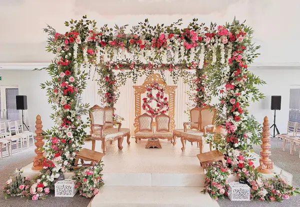 Mandap with rose garland pillars and a floral canopy