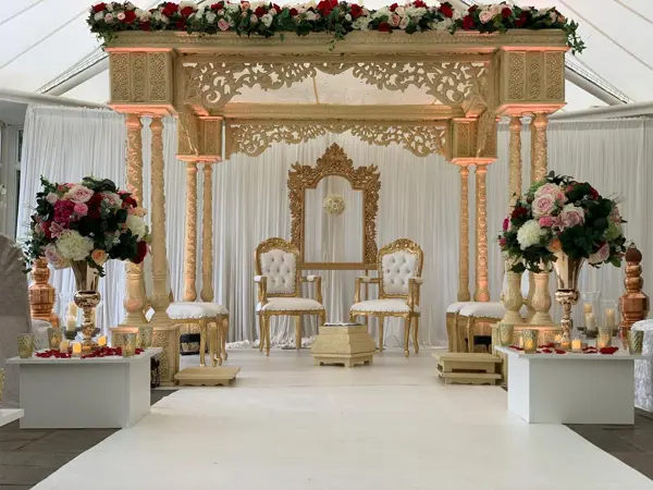 Carved ivory mandap with floral arrangements and chairs