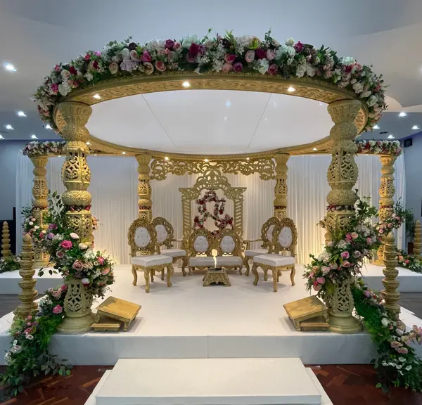 Round gold mandap on a raised white stage