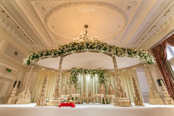 Floral mandap beneath an ornate carved archway