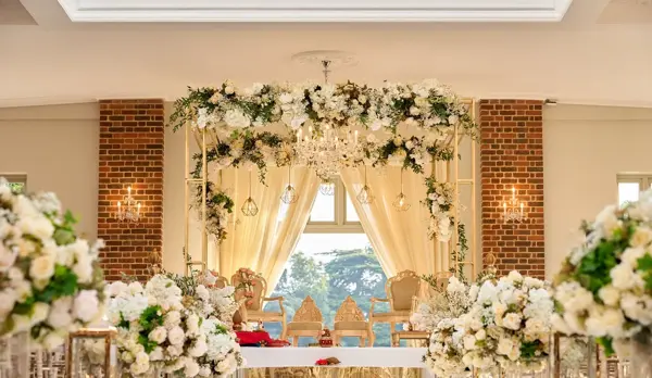 Mandap framed with white flowers and drapes in a period room