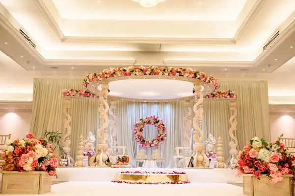 Ivory mandap with floral canopy and a floral ring backdrop
