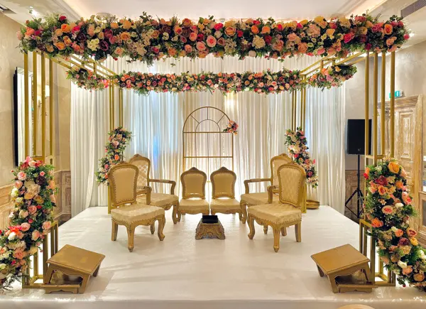 Gold frame mandap with heavy floral canopy and gold chairs