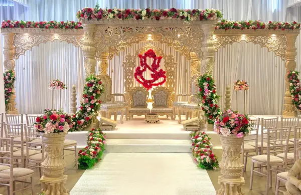 Ivory and gold mandap stage with floral pillars along the aisle