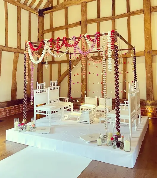Simple mandap with garlands in a timber-framed barn