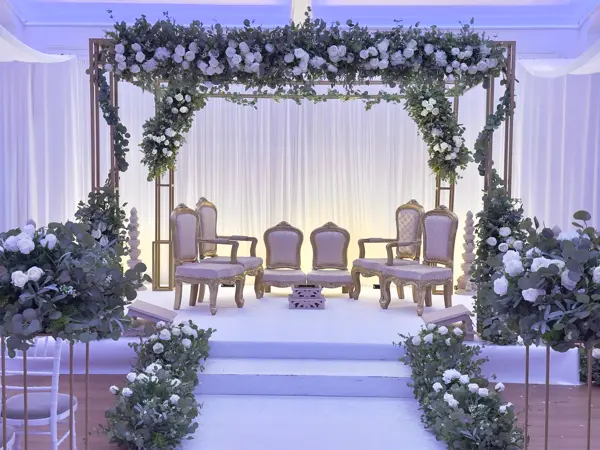 Open frame mandap covered in white and lilac flowers
