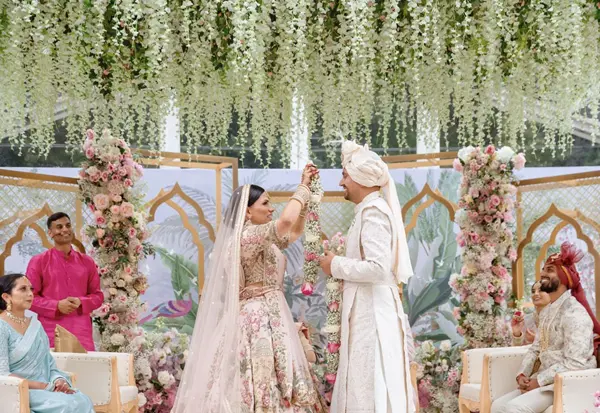 Couple during the ceremony beneath hanging white flowers