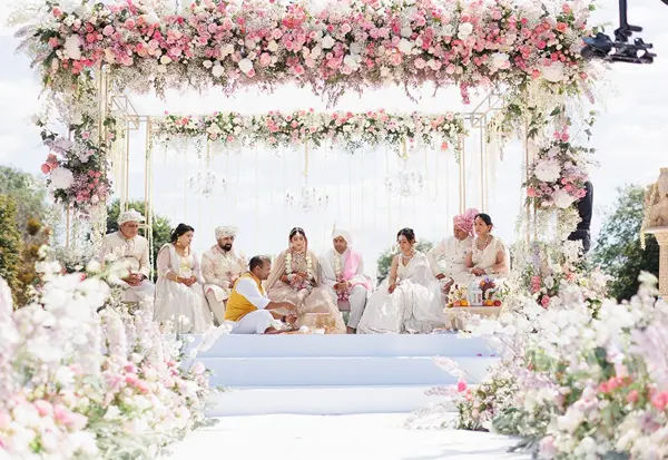 Families seated under a pink floral canopy during the ceremony