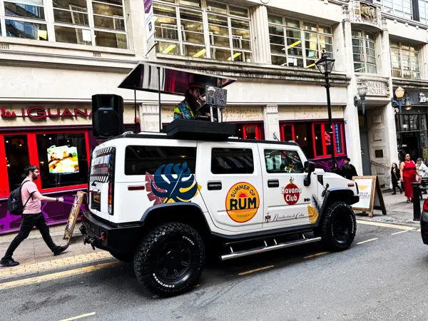 White branded DJ truck with a DJ on top in a busy street