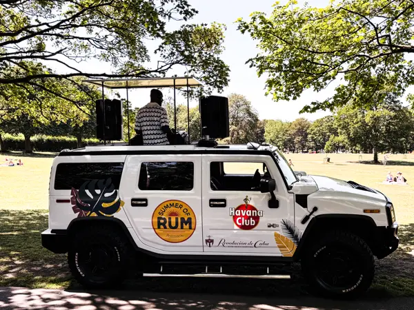 White DJ truck with a DJ on the roof in a park