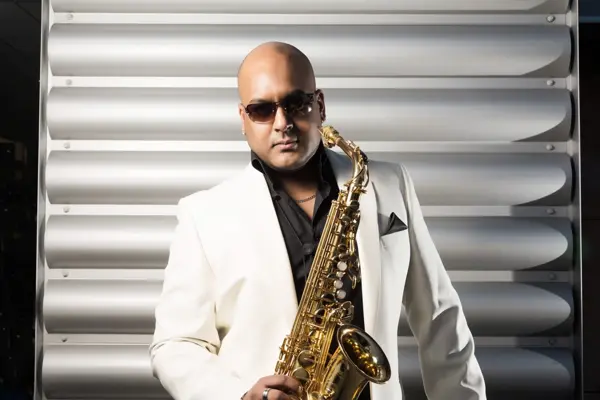 Saxophonist in a white jacket holding a gold saxophone