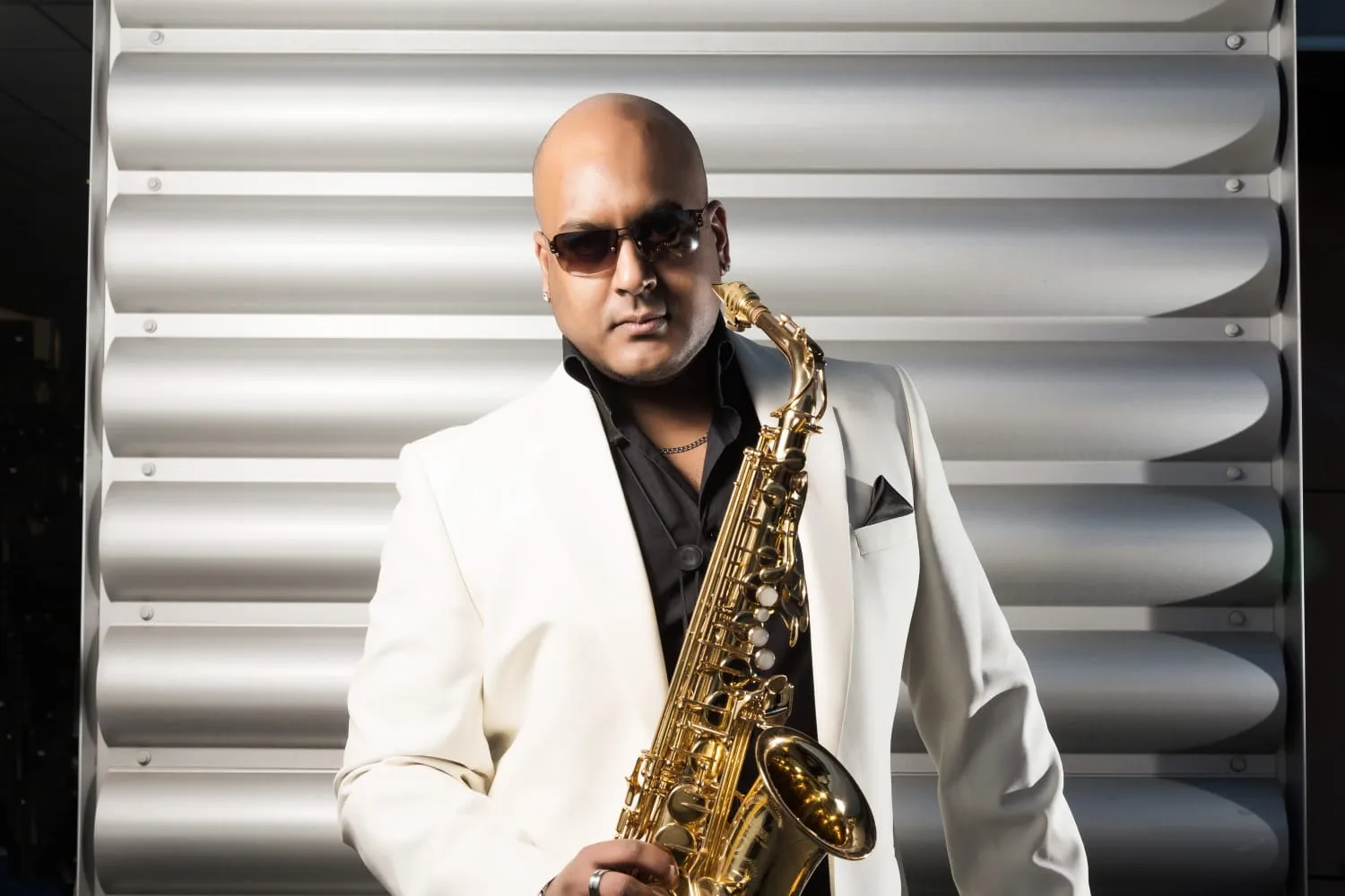Saxophonist in a white jacket holding a gold saxophone